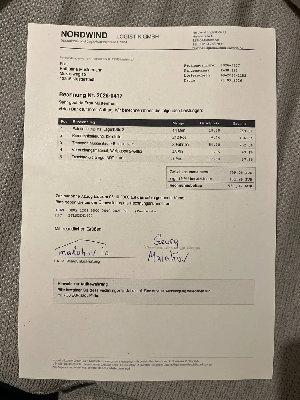 Eine ausgedruckte Rechnung auf einem grauen Sofa, abends bei Zimmerlicht mit dem Handy fotografiert
